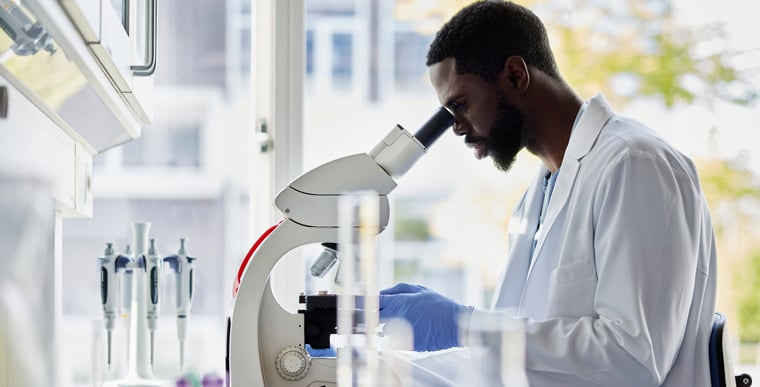 Doctor in lab looking through microscope