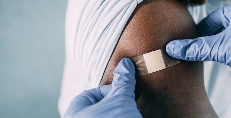 Doctor putting bandage on patients arm after injecting biologics for eczema