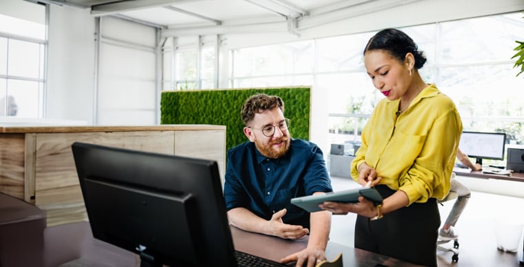 Woman showing man information on tablet in office
