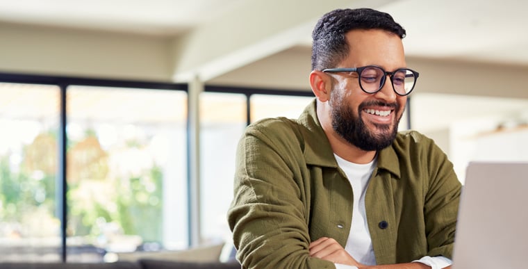 Man smiling while working on laptop