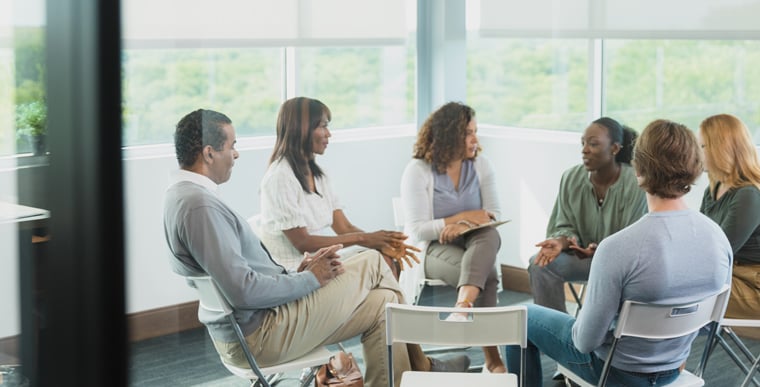 group of people sitting in circle talking