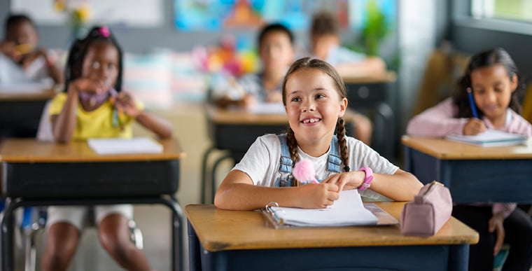 young girl smiling at her desk during school