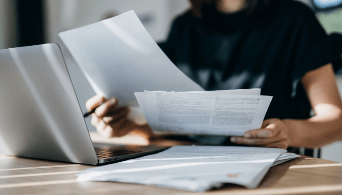 a person reading papers and looking at a computer