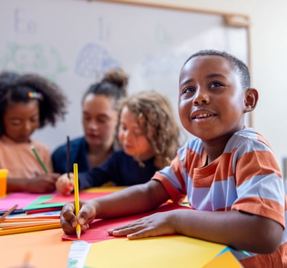 Close up picture of boy sitting at desk with pencil in hand