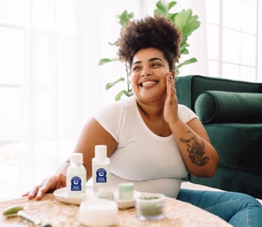 Black woman sitting on the floor and applying Seal of Acceptance products