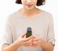 A woman holds a skincare product bottle, considering a purchase.