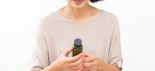 A woman holds a skincare product bottle, considering a purchase.