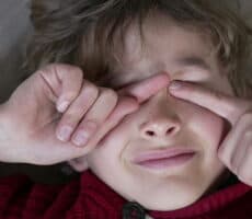 Child rubbing their eyes, illustrating eye irritation and discomfort associated with eczema and eye health issues.