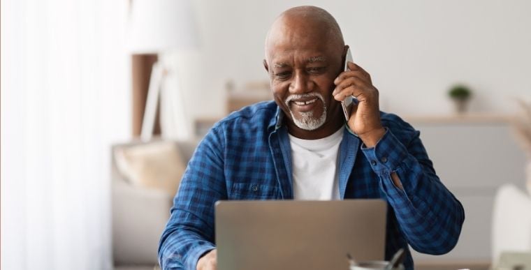 A man talks on the phone and looks at a computer.