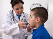 Doctor administers an inhaler to boy with asthma