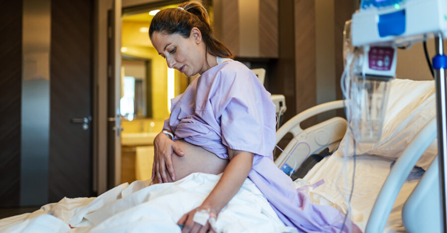 pregnant woman in hospital holding hand against stomach