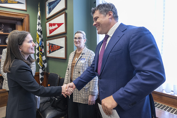 NEA Ambassador shakes hands with [Representative or staffer’s name], surrounded by NEA staff and board members in a representative’s office.