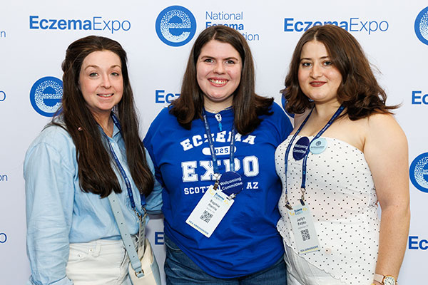Sophie Harris (center) smiling with two other attendees in front of a backdrop at Expo 2025